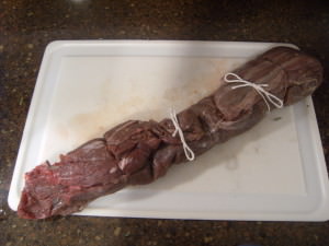 A whole beef tenderloin that has been marinated and tied for even cooking.