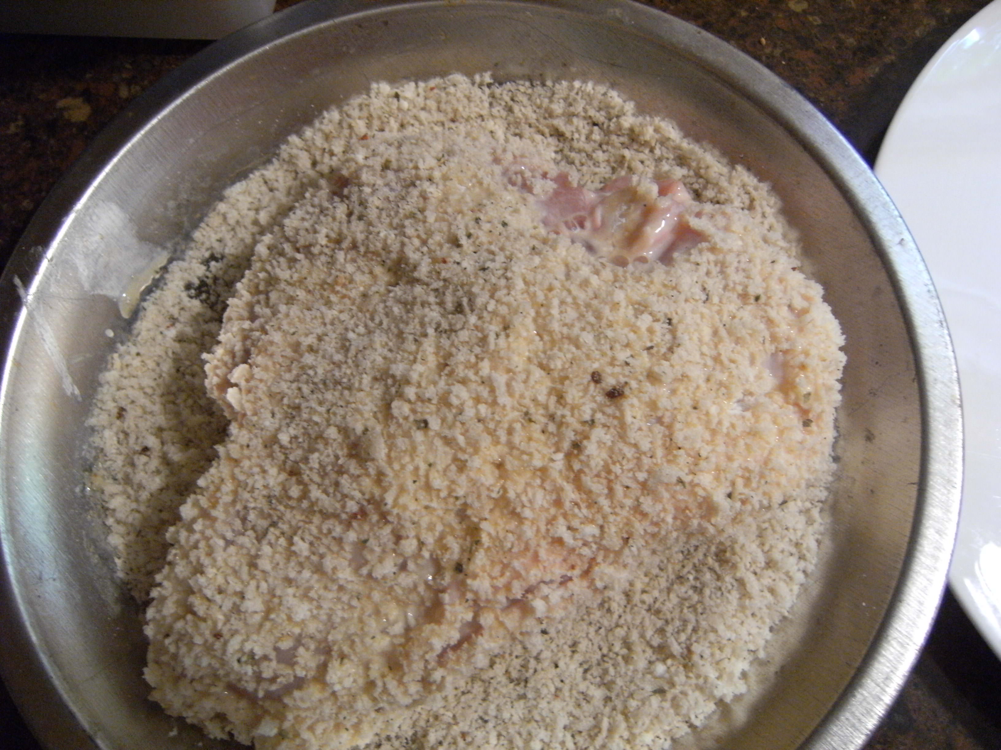 coating chicken breasts with seasoned Panko bread crumbs