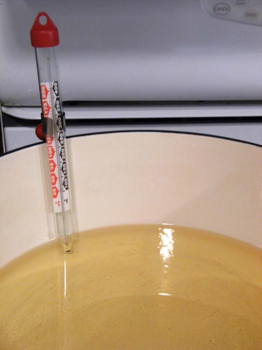 checking the temperature of hot oil with a candy thermometer