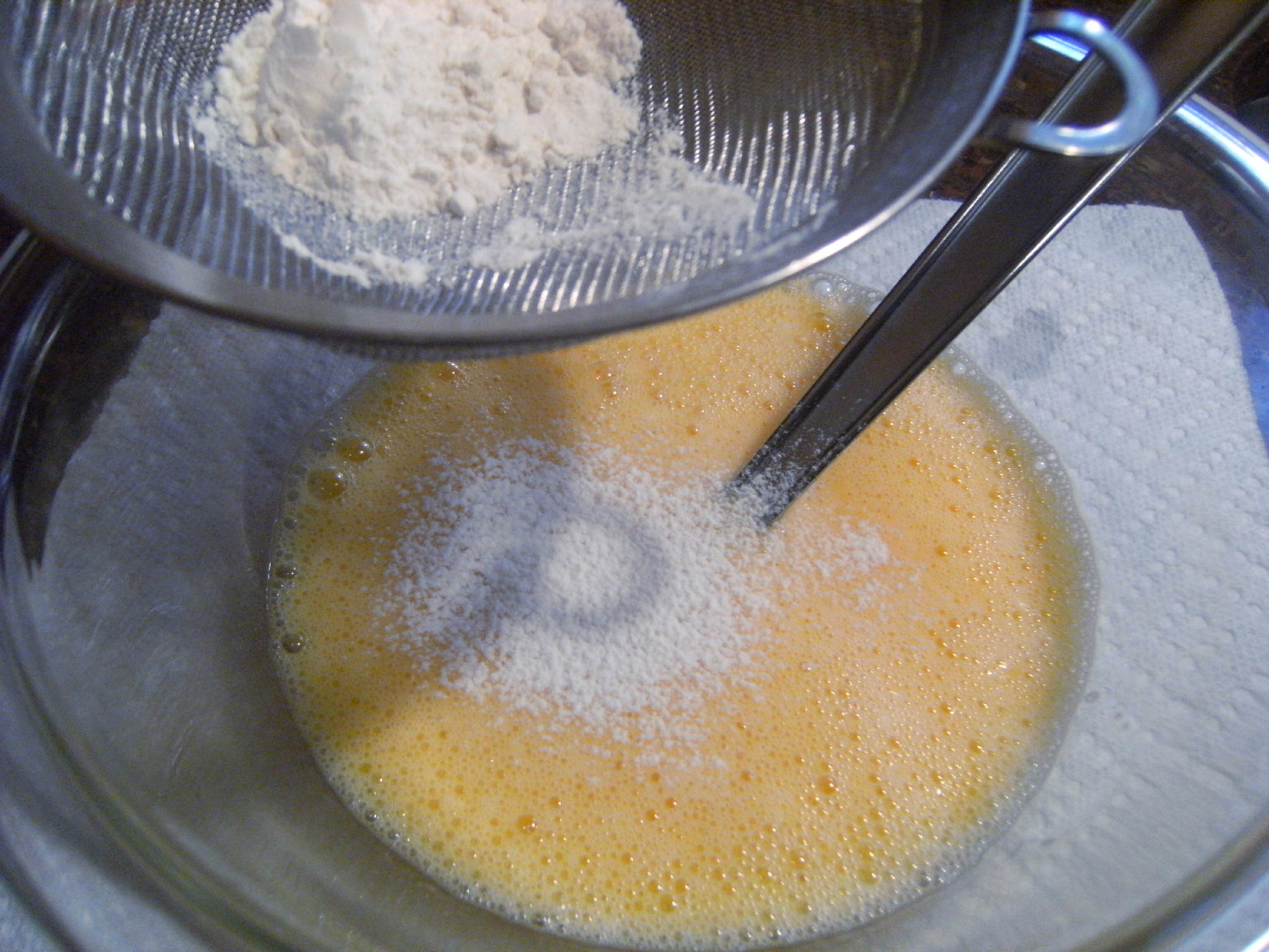 sifting flour into a chocolate ugly cake batter
