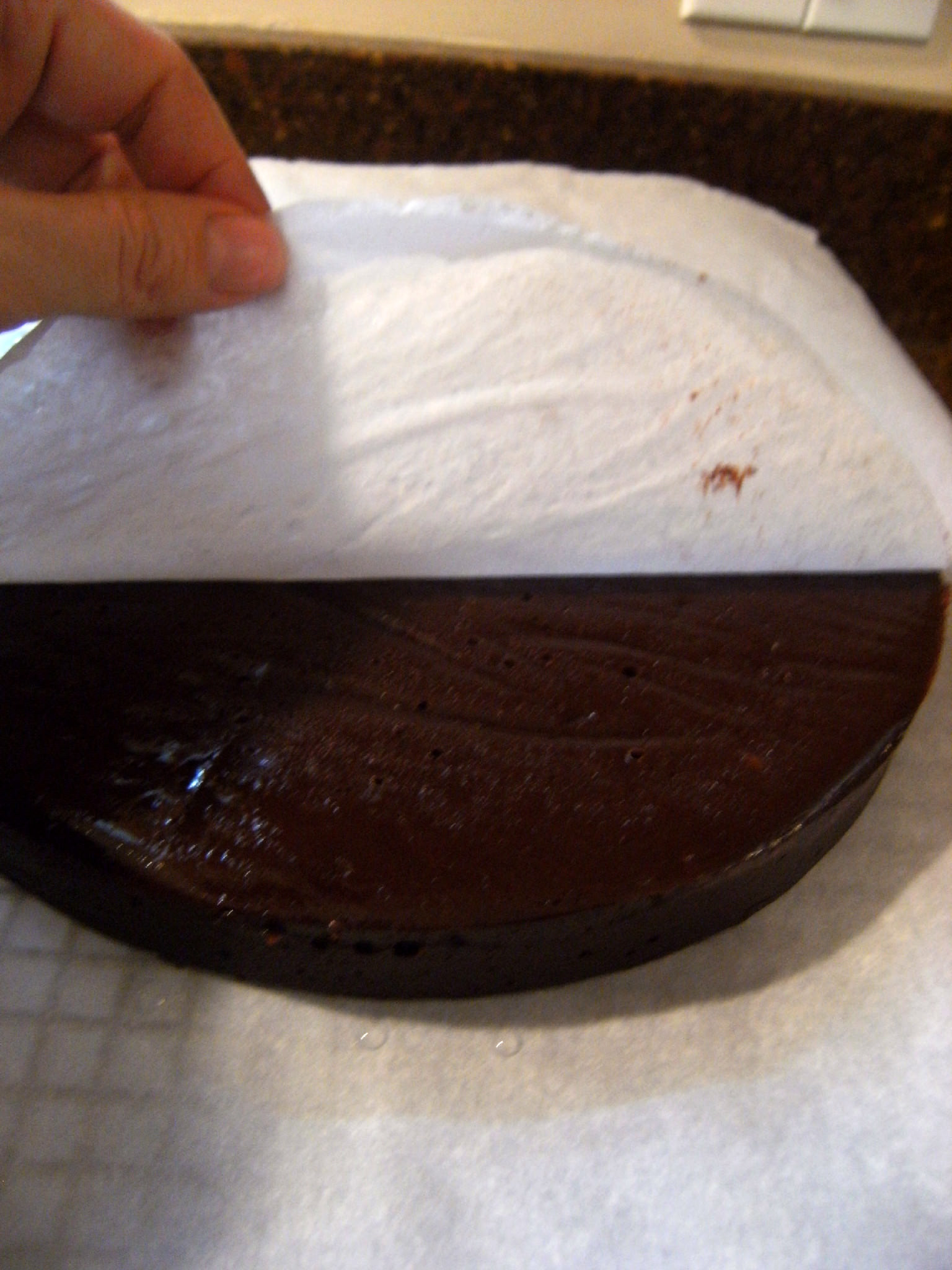 Removing parchment paper from the bottom of a chocolate ugly cake.
