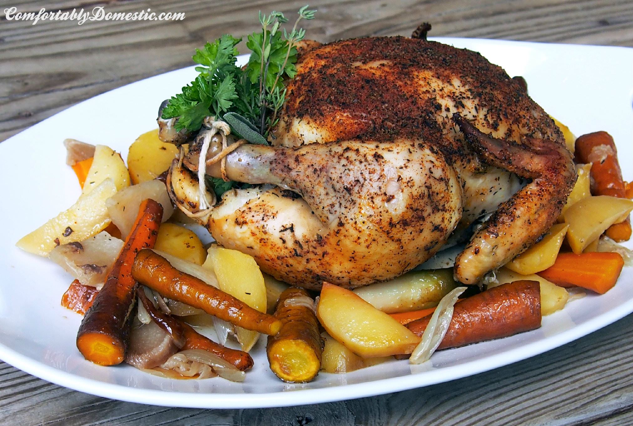Slow cooker whole roasted chicken is the perfect dinner! Succulent, seasoned chicken on a bed of root vegetables, slow roasted all day for a flavorful and fragrant weeknight meal. | ComfortablyDomestic.com