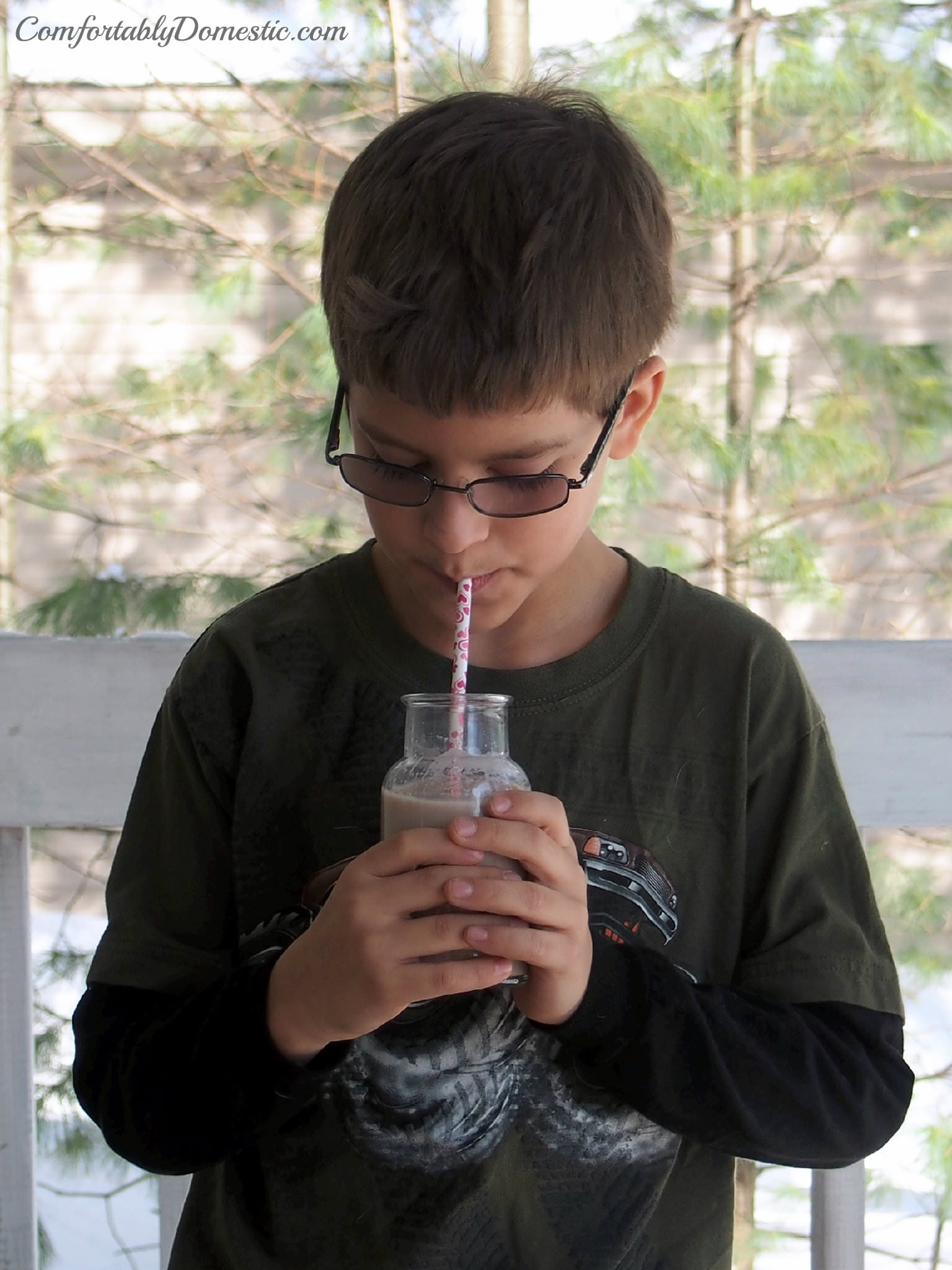 boy drinking chocolate milk made with homemade chocolate syrup.