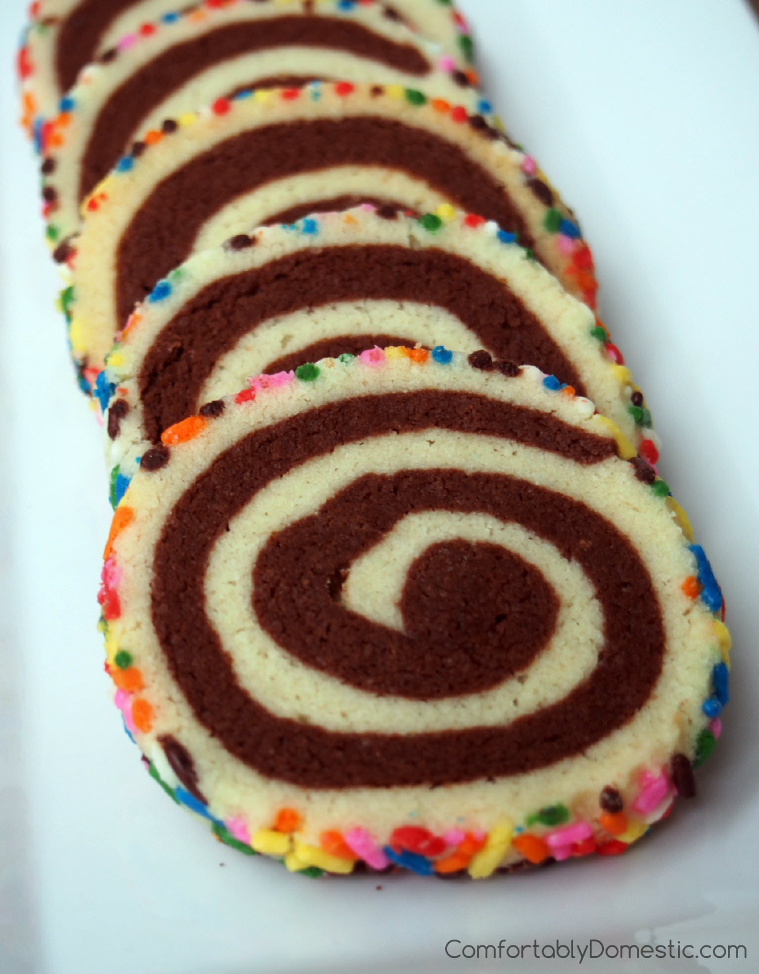 Shortbread pinwheels, also known as happiness cookies, are buttery vanilla and chocolate shortbread cookies presented in a fun pinwheel design, with colorful sprinkles for an added touch of whimsy. | ComfortablyDomestic.com