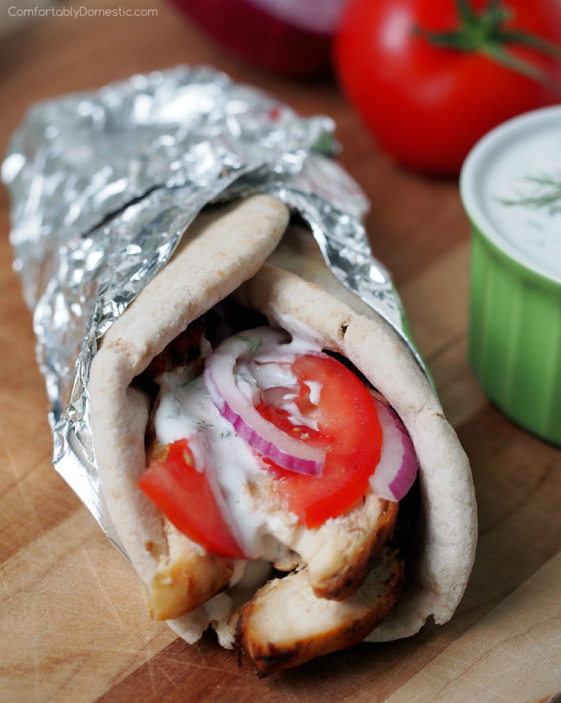 Grilled-Chicken-Gyros - Tender, souvlaki-style grilled chicken topped with a flavorful garlic, dill, and cucumber tzatziki yogurt sauce, ripe tomatoes, and thinly shaved red onion wrapped in warm pita bread. | ComfortablyDomestic.com