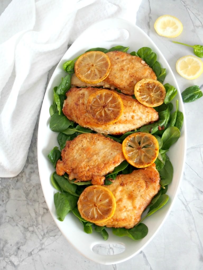 Lemon butter chicken is boneless chicken breast, pan seared in butter with garlic and lemon, then served over wilted spinach. | ComfortablyDomestic.com