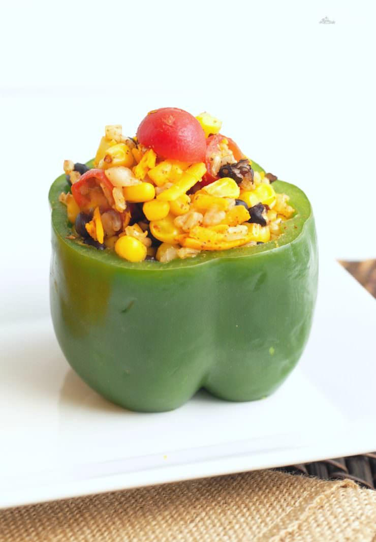 Vegetarian-Stuffed-Peppers-add-Tex-Mex-flavor to sweet bell peppers filled with a combination of chewy brown rice, tender black beans, garden fresh vegetables, tangy cheese, and blend of southwest seasonings to make these healthy morsels anything but bland or ordinary.
