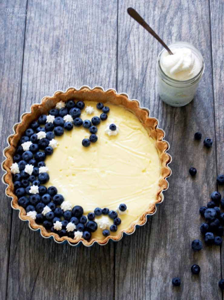 Vanilla-Custard-Tart-with-Blueberries-and-Cream is a fresh and light summer dessert featuring creamy vanilla bean custard topped with a smattering of fresh blueberries and a touch of whipped cream.