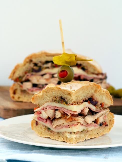 Light-Chicken-Muffaletta-Sandwich takes a healthier spin with tender chicken, smoked ham, provolone, and the classic olive salad sandwiched between soft and crusty bread.