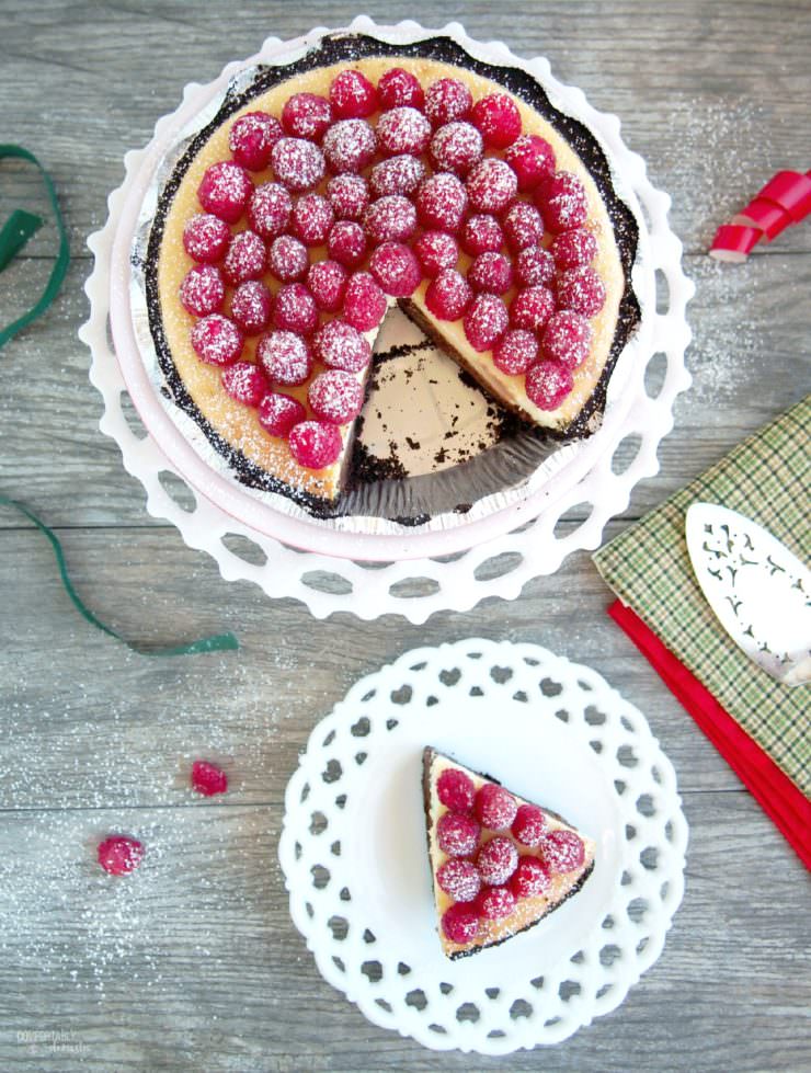 Chocolate-Layer-Cheesecake has a rich layer of vanilla cheesecake resting atop a decadent layer of chocolate cheesecake nestled in a chocolate cookie crust. Topped with fresh raspberries and whipped cream, this cheesecake is a showstopper!