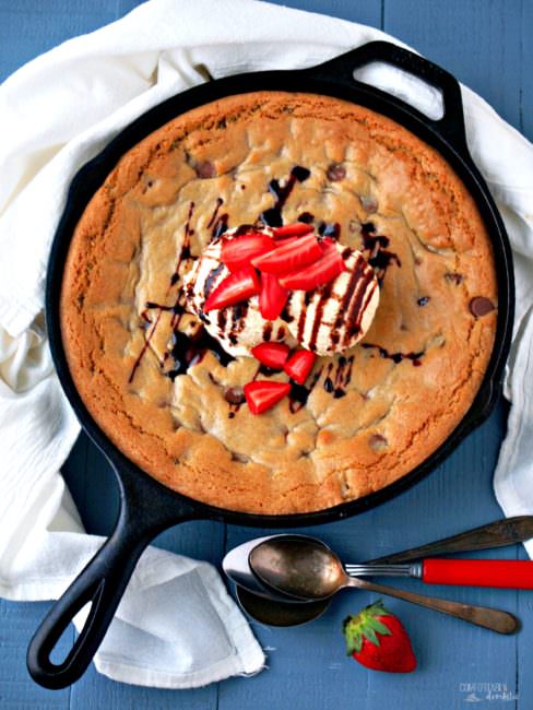 Skillet-Chocolate-Chip-Cookie-Sundae takes all of the iconic comfort of the classic cookie and serves it up in a cast iron skillet. The gloriously warm and gooey cookie is served family style with vanilla ice cream, chocolate syrup, and fresh strawberries.