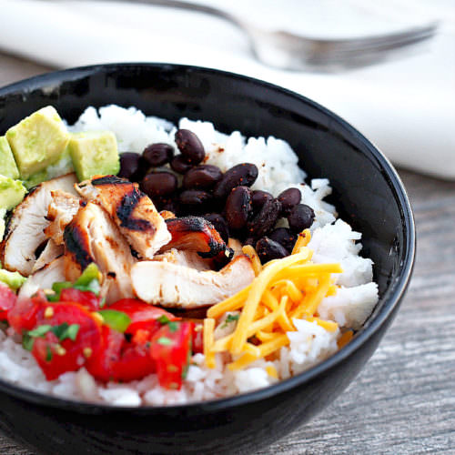 Chicken-Burrito-Bowls nestle perfectly seasoned chicken atop a bed of fluffy lime-cilantro rice along with roasted black beans and all the trimmings for a healthy dinner with loads of flavor. A copy cat recipe of the Chipotle restaurant favorite.