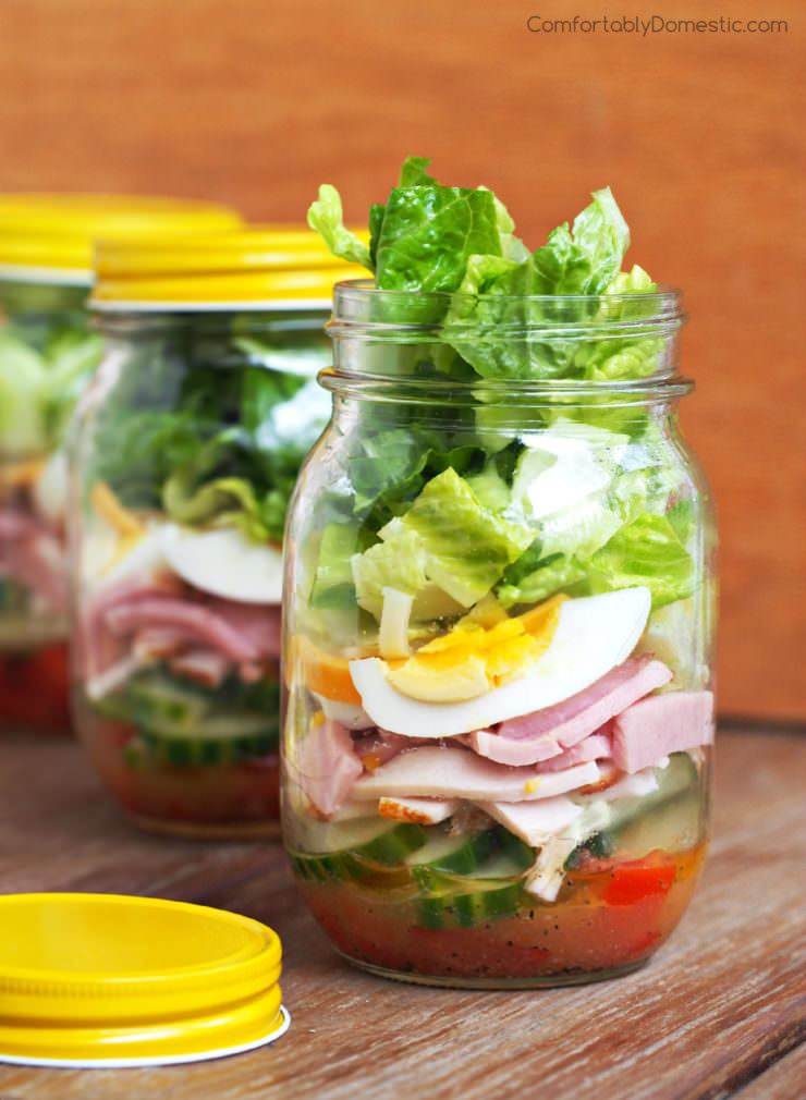 series of chef salads in jars with yellow lids.
