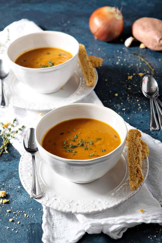 two-white-bowls-filled-with-vegetarian-sweet-potato-bisque-soup-with-spoons-and-bread