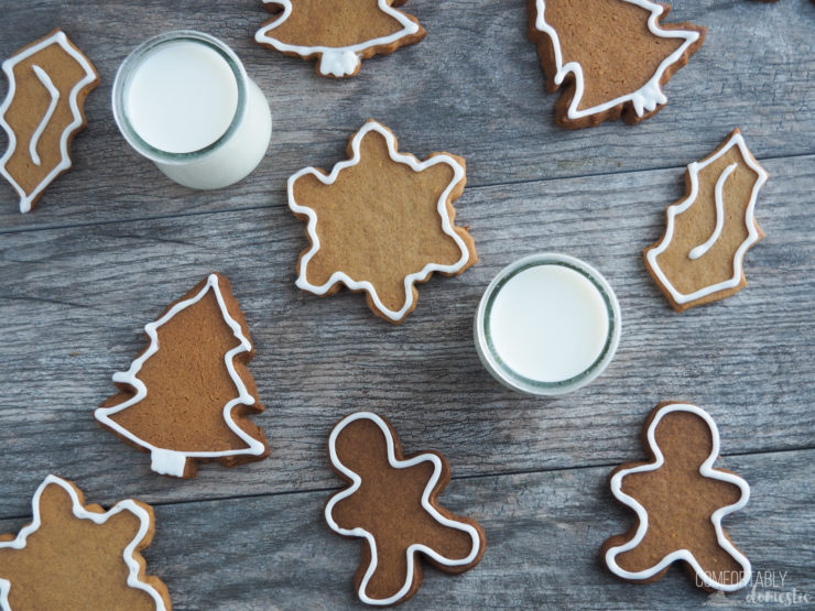 Landscape view of a scattering of gingerbread cut out cookies with two glasses of milk. 