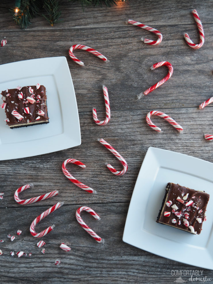 Overhead photo of peppermint cheesecake brownies on white plates with candy canes scattered around them.