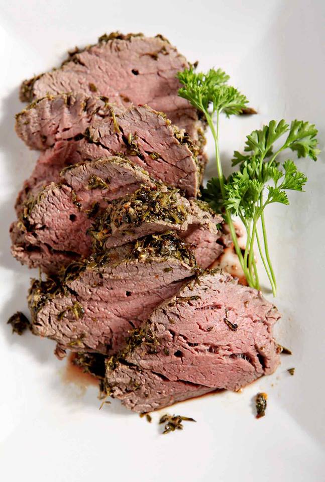 slices of herb crusted beef tenderloin on a white plate