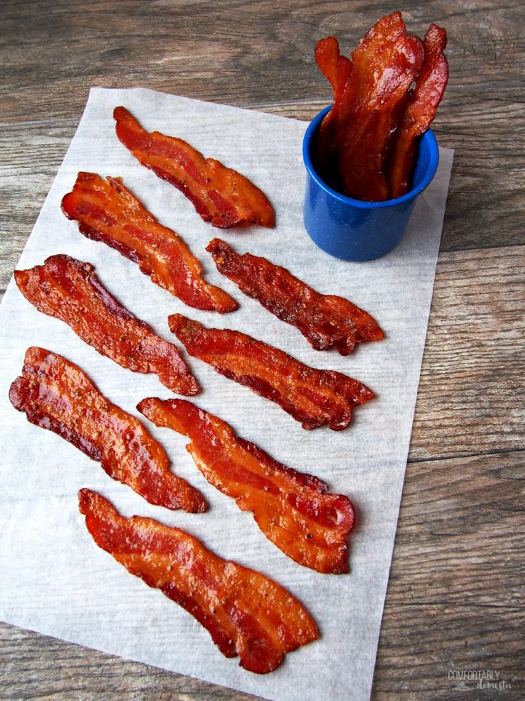 Overhead photo of crisp candied maple bacon on parchment and a wood background.