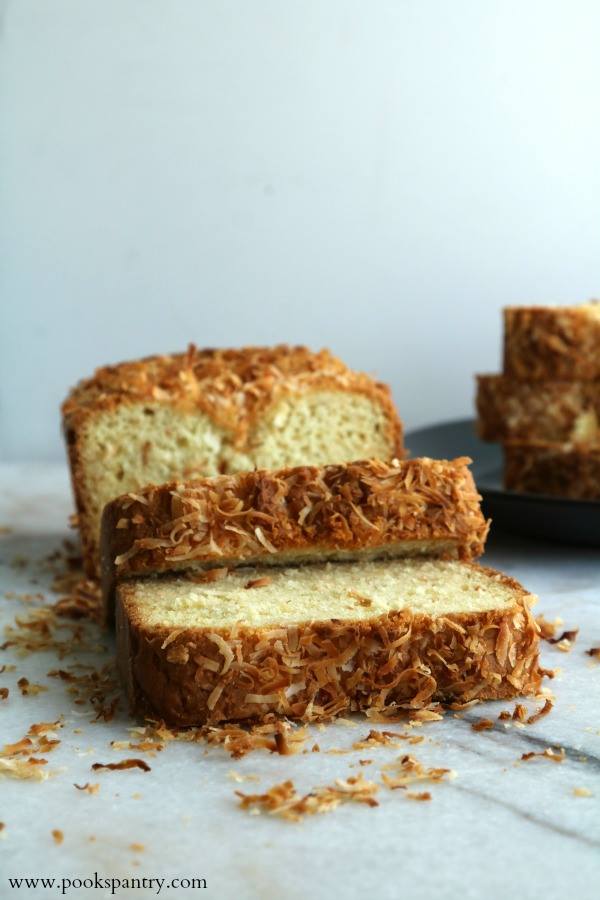 Slices of coconut bread with toasted coconut flakes on top, resting on a white background.