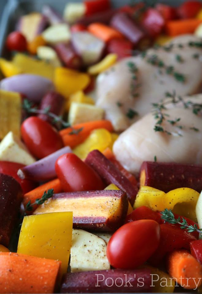 Overhead photos of multicolored carrots, tomatoes, sweet peppers, and boneless skinless chicken breasts on a sheet pan. 