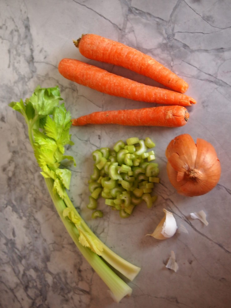Carrots, celery, garlic, and onions on a marble background. 