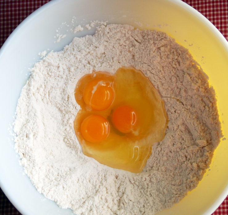 bowl of flour with three eggs in the center