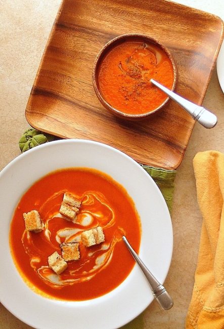 tomato soup in a white bowl with croutons on top.