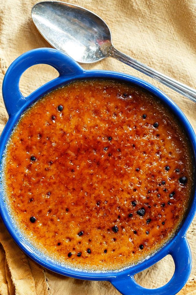 Butterscotch creme brulee in a blue crock with caramelized sugar topping.