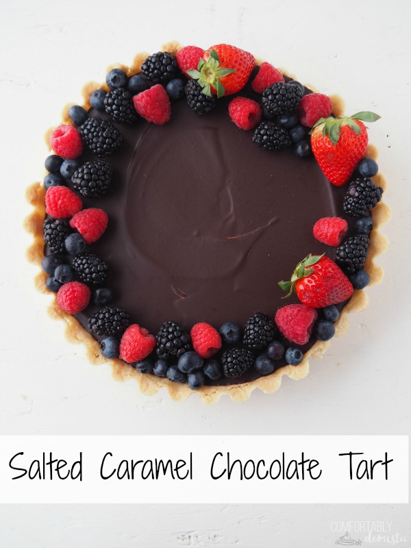 Overhead photo of a Salted Caramel Chocolate Tart garnished with fresh blueberries, strawberries, raspberries, and blackberries on a white background. 