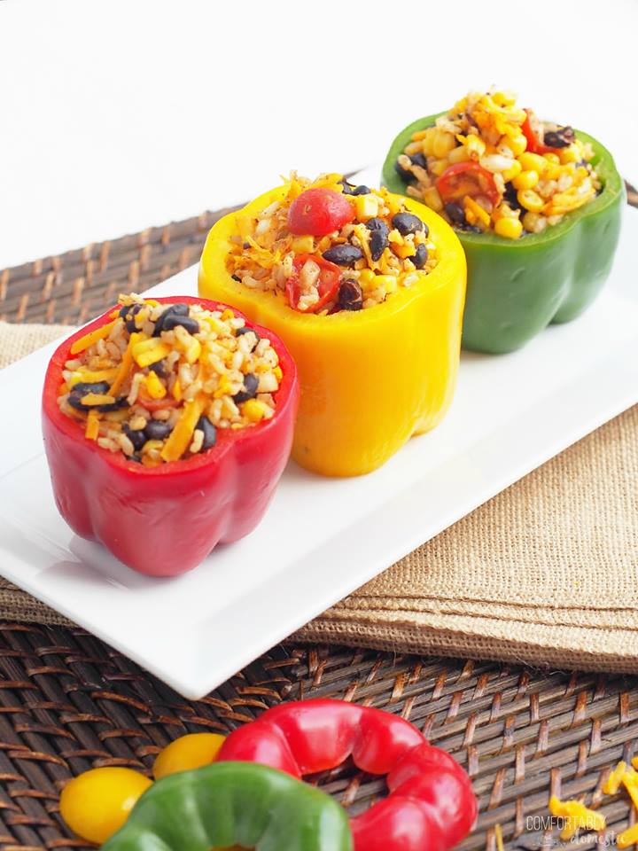 Stuffed red, yellow, and green bell peppers on a white plate.