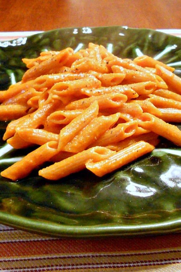 Penne pasta with creamy vodka sauce on a green plate. 