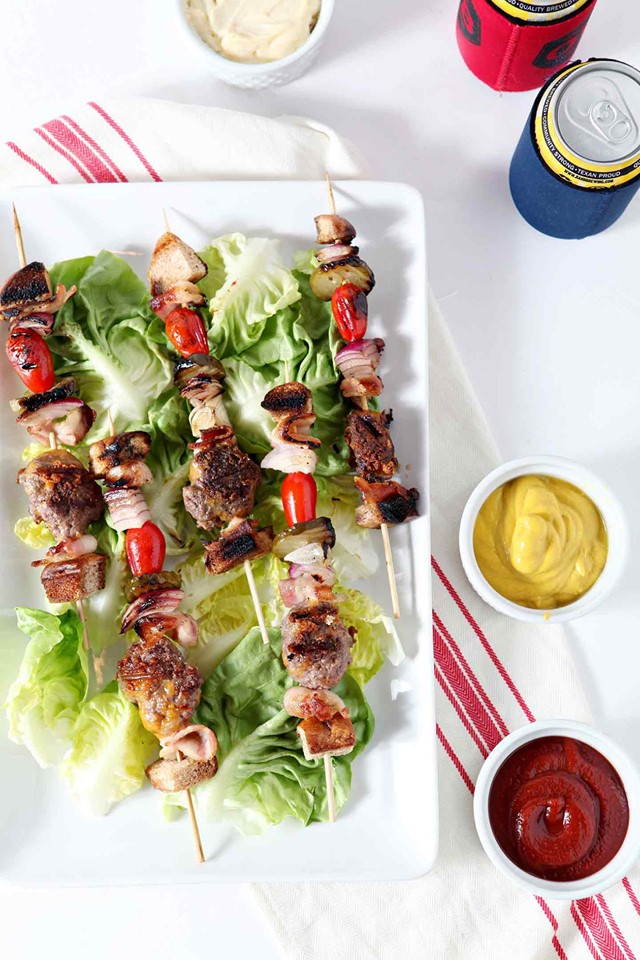 cheeseburger-kebabs on a bed or romaine lettuce on a white platter. 