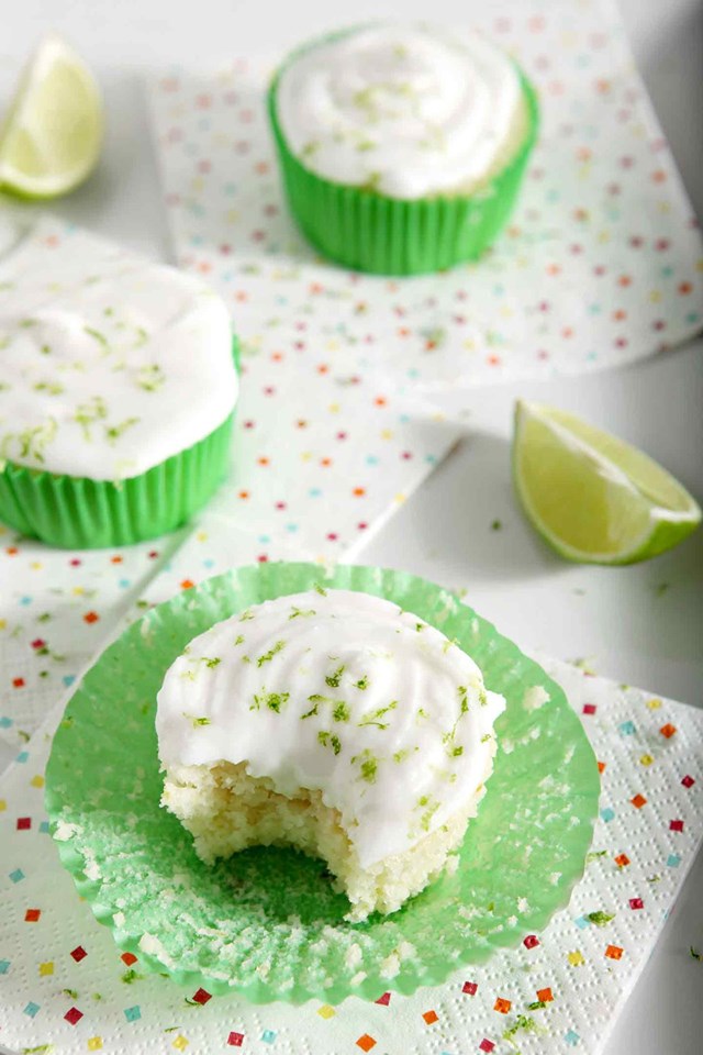 three frosted maragrita cupcakes with green sprinkles and a lime wedge