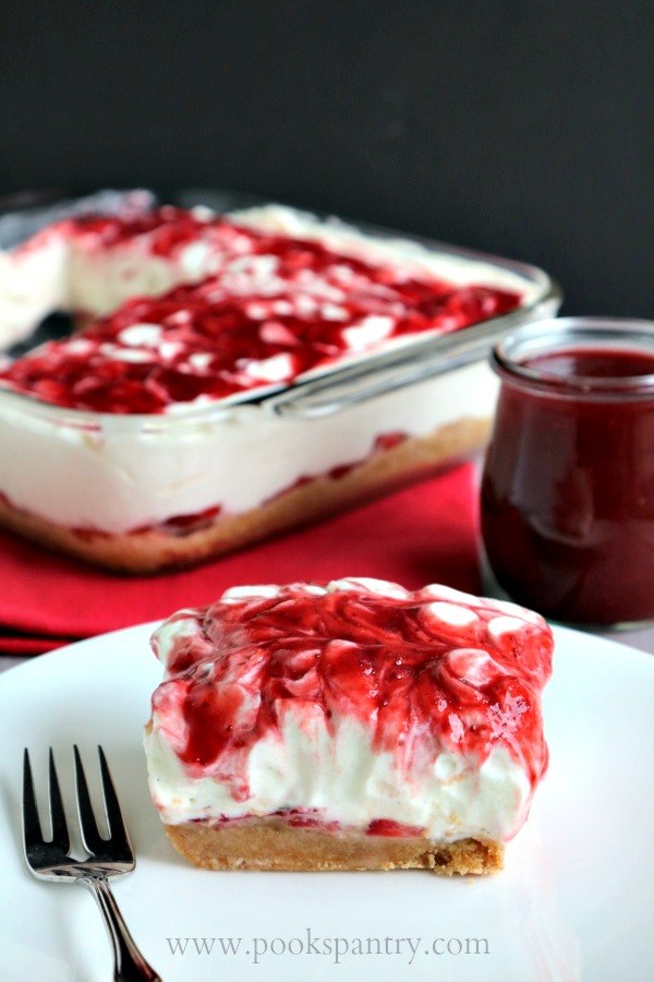 no-bake-strawberry-cheesecake-bars on a white plate with jam in the background.