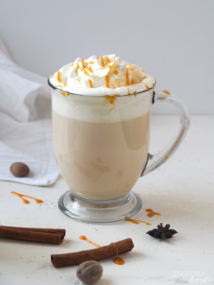 Caramel Apple Chai Latte in a glass mug with whipped cream, freshly grated nutmeg, and caramel sauce.
