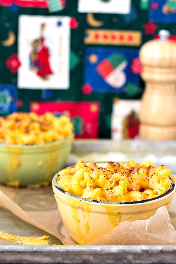 two-gooey-bowls-of-creamy-macaroni-and-cheese with melted cheese dripping down the sides.