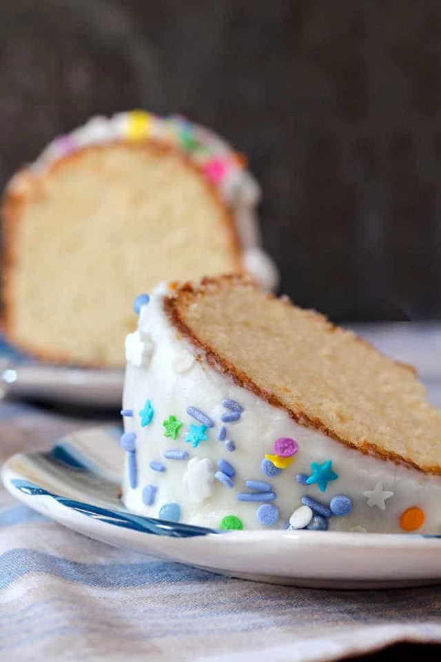 two slices of pound bundt cake with vanilla frosting and multicolored sprinkles