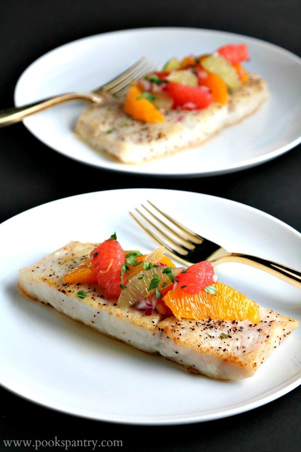 whitefish-with-citrus-on-top on white plates with a fork.