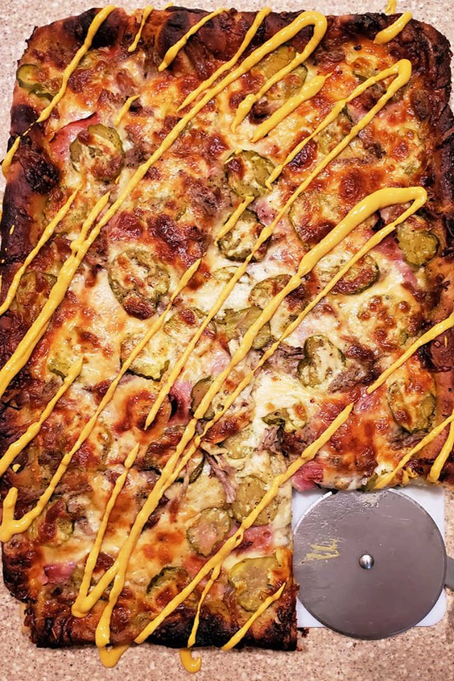 close up photo of pizza with cuban sandwich toppings.