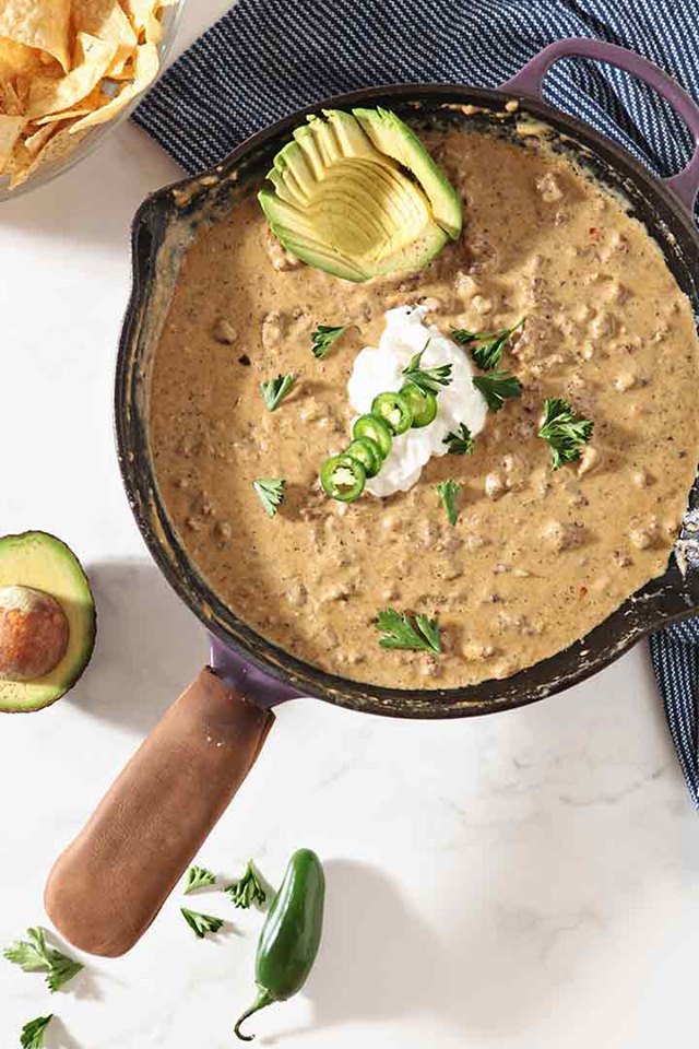 Cast iron skillet filled with warm queso cheese dip. 