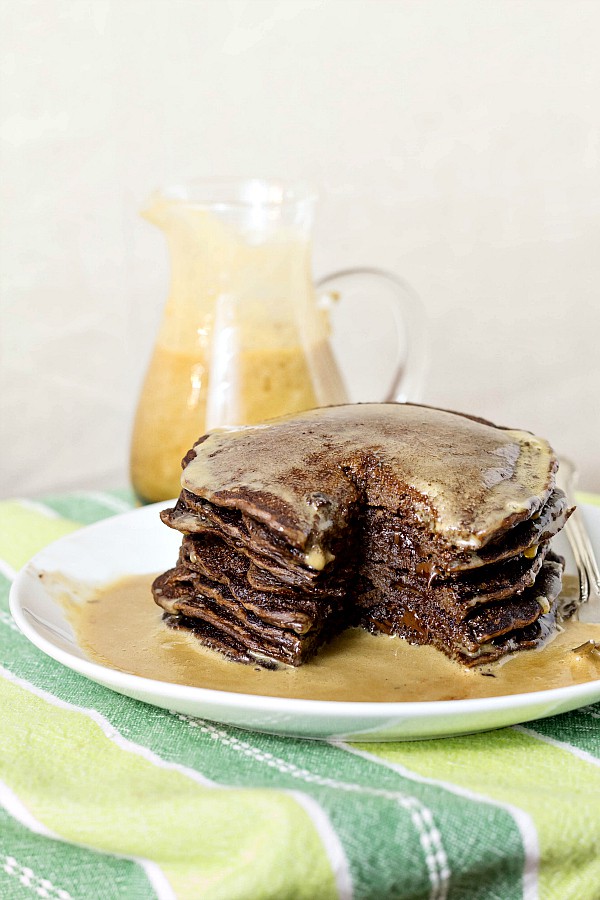 A tall stack of yeasted chocolate chip pancakes on a white plate.