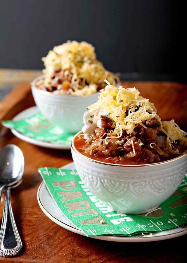 Two white bowls heaping with shiner bock flavored chili and cheese.