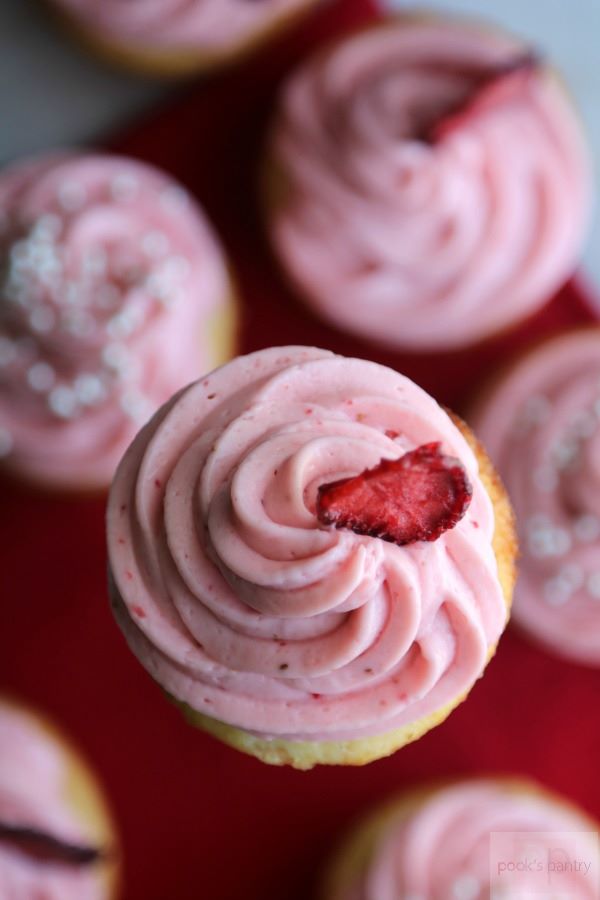 aerial view of vanilla cupcakes with strawberry cream cheese frosting. 