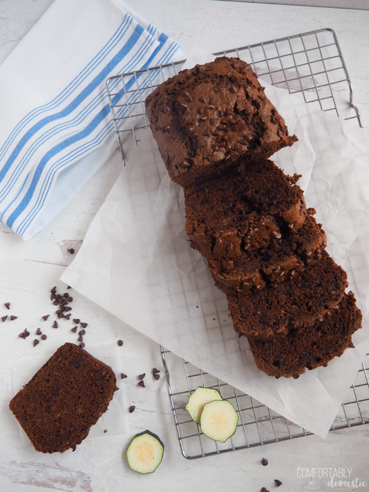 Thick slices of double chocolate zucchini bread with melty chocolate chips on white parchment paper.