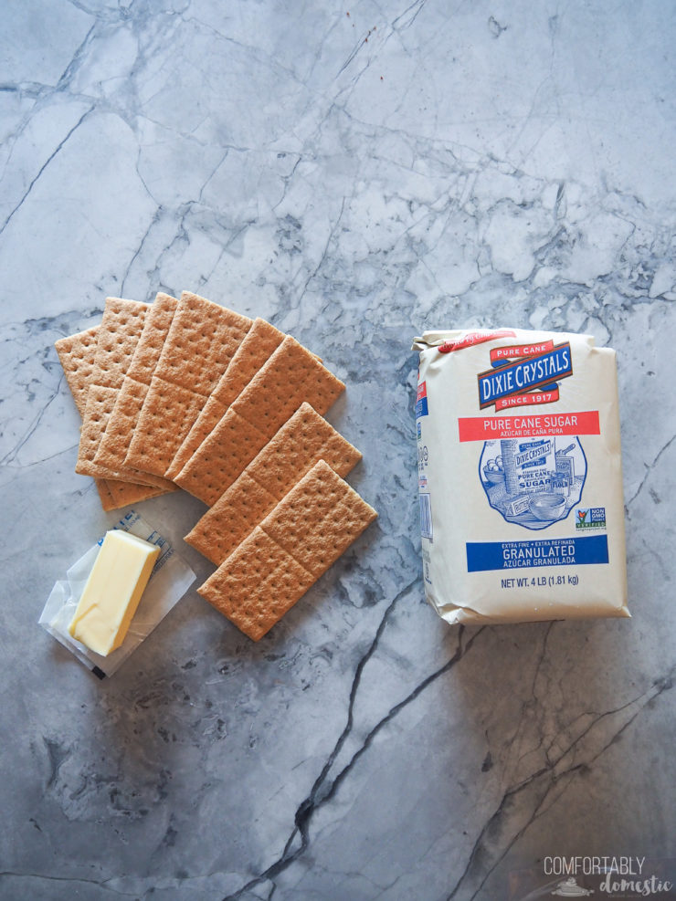 Graham crackers, butter and sugar set on white marble to make perfect crust. 